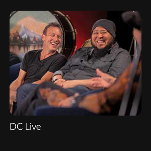 Two artists sitting and laughing with text "DC Live".